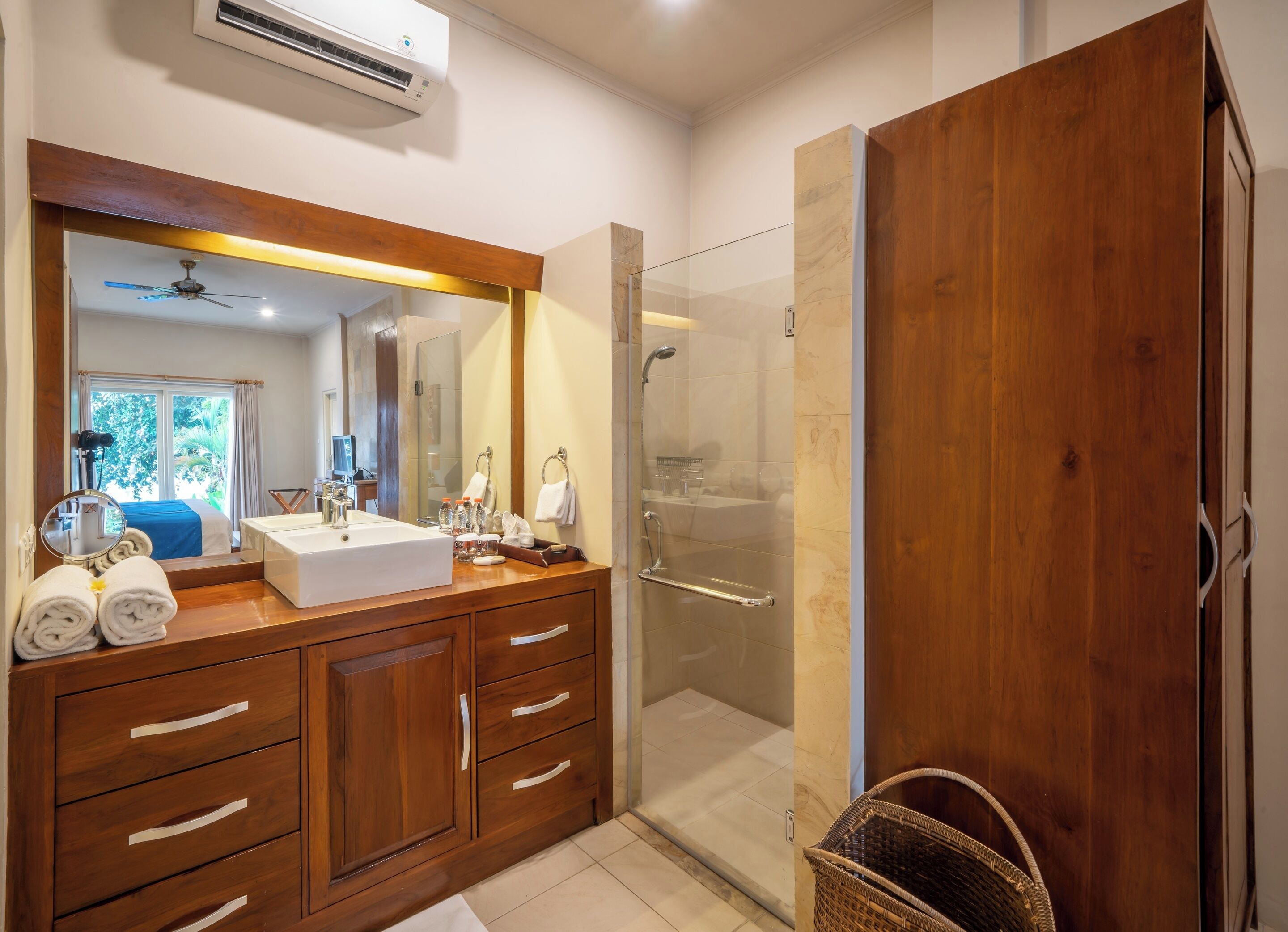 Une salle de bain moderne avec un meuble-lavabo en bois, un grand miroir, une cabine de douche et une vue sur l’extérieur.