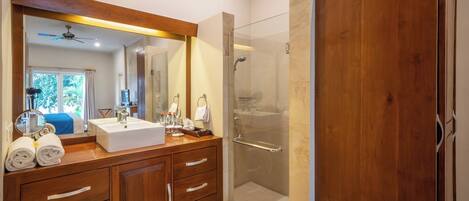 Une salle de bain moderne avec un meuble-lavabo en bois, un grand miroir, une cabine de douche et une vue sur l’extérieur.