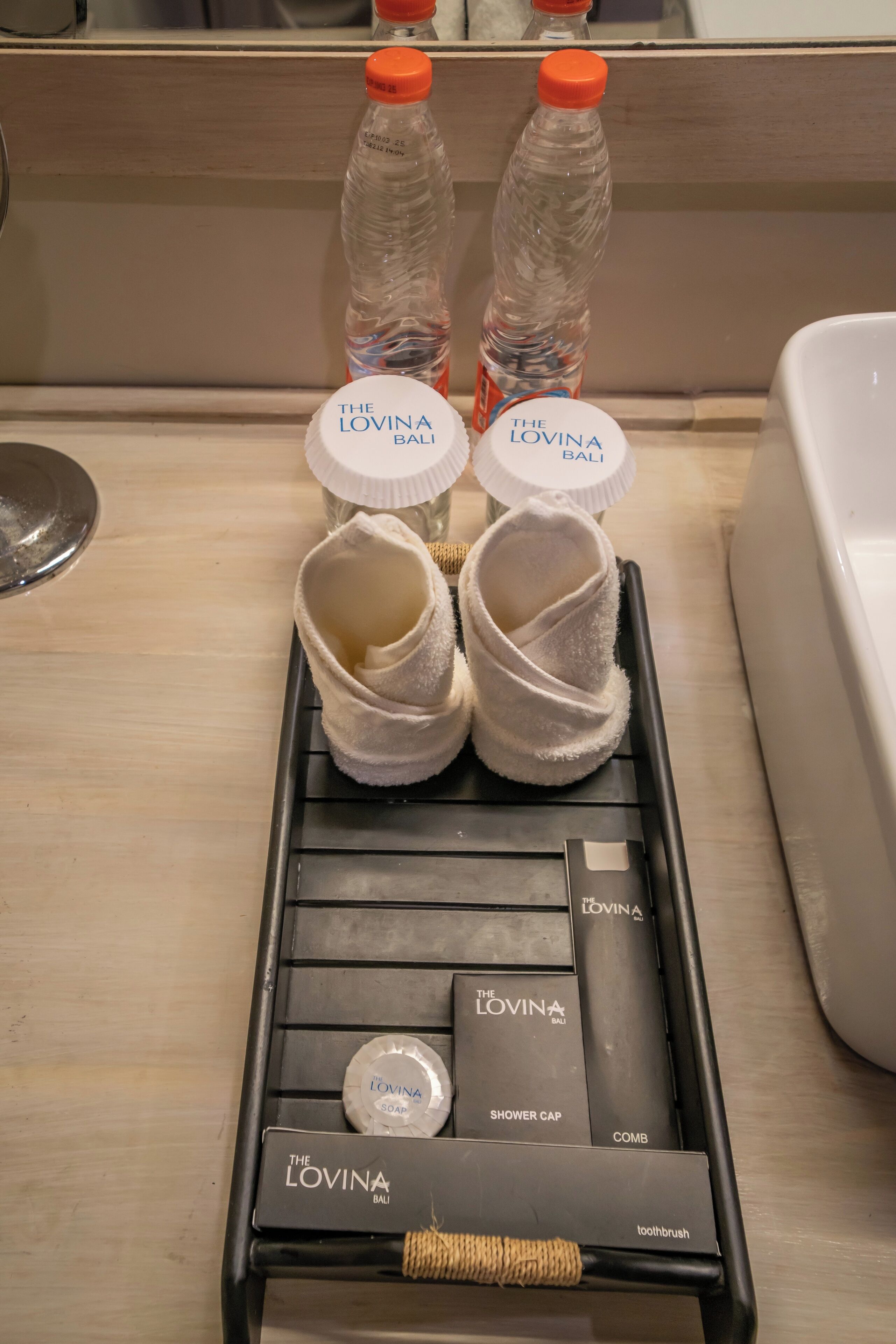 Een badkamermeubel in een hotelkamer met toiletartikelen en een handdoekrek.