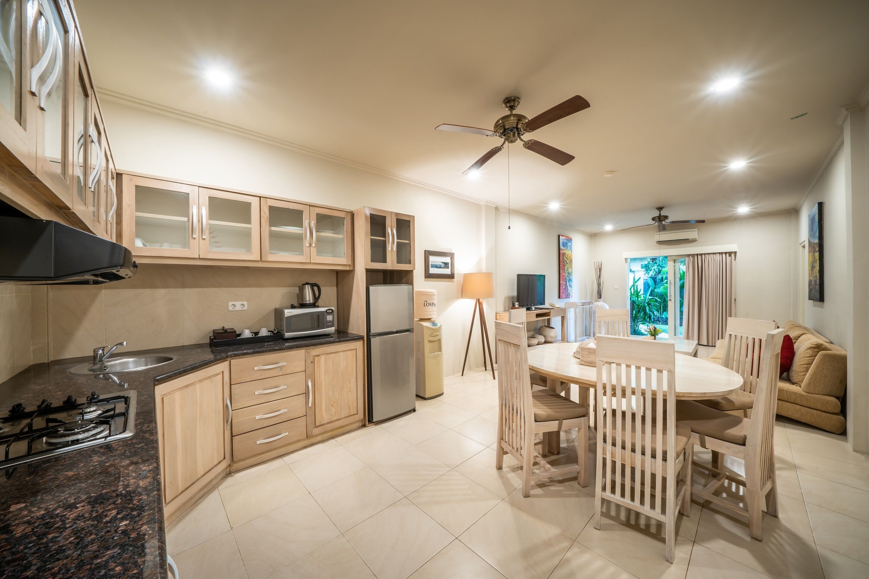 A modern kitchen with a gas stove, microwave, and refrigerator. There is a dining area with a table and chairs.