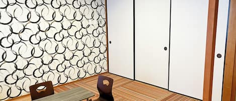 A traditional Japanese room with tatami flooring, a low table, and a sliding door.