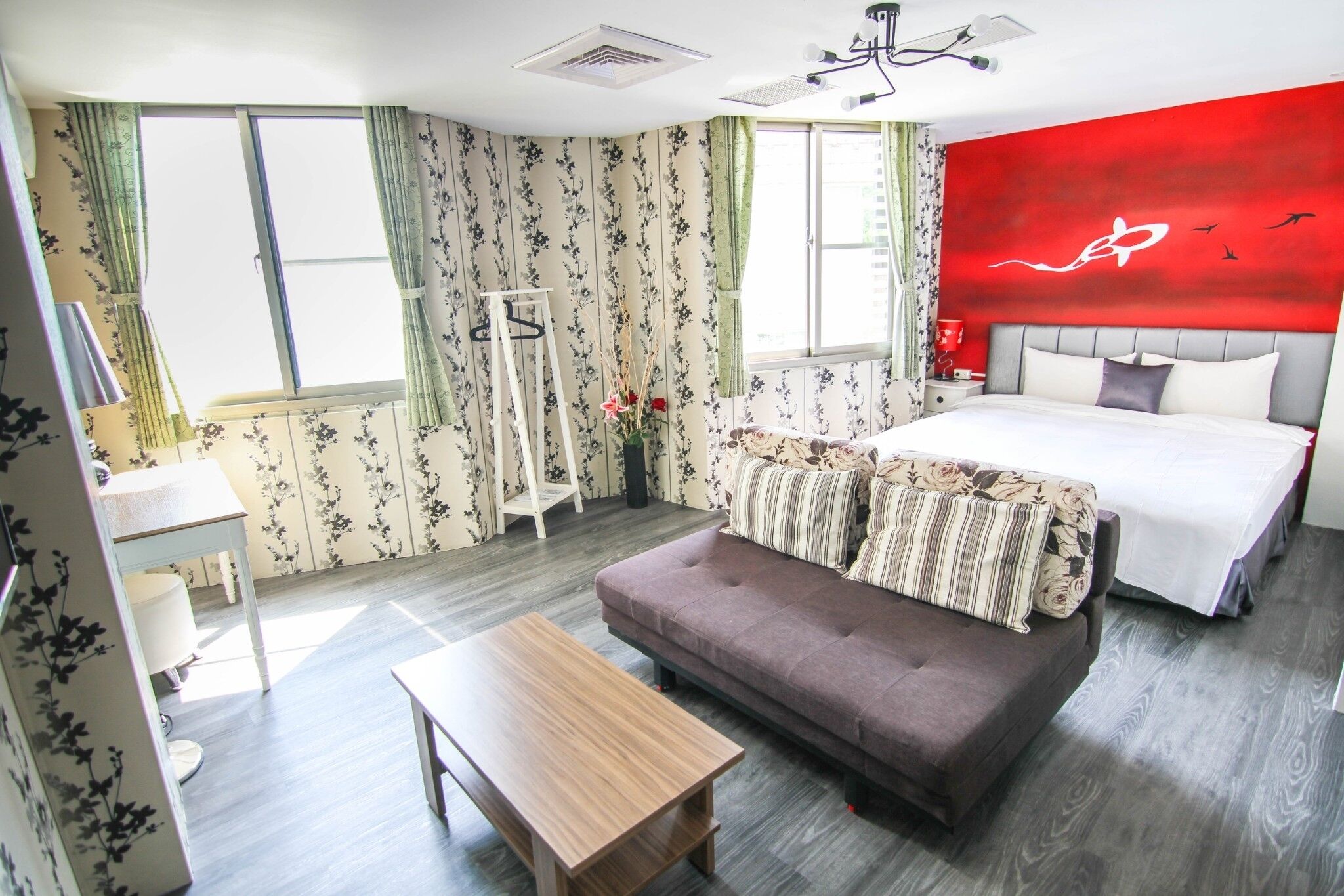 Un dormitorio con cama, sofá, mesa y ventana con cortinas.
