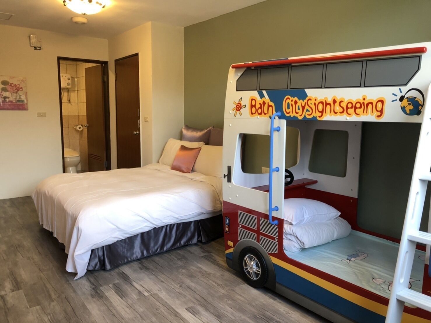 Un dormitorio con cama, una cama litera con motivos turísticos y suelo de madera.