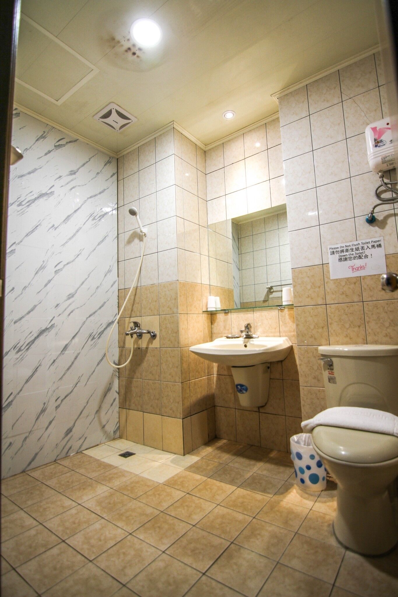 A bathroom with a shower, sink, toilet, and a mirror.