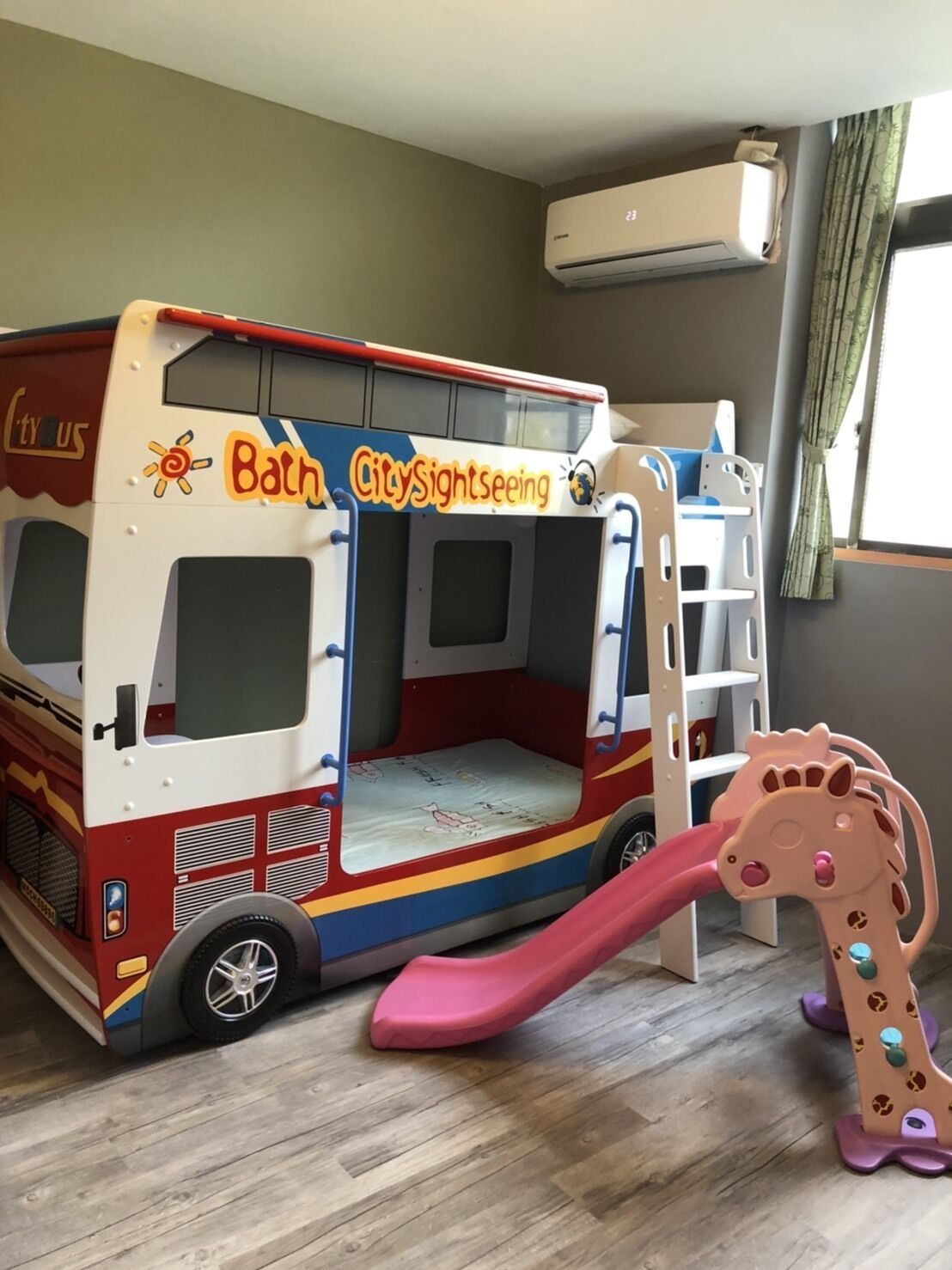 A play area with a colorful bus-themed play structure, a slide, and a giraffe toy.