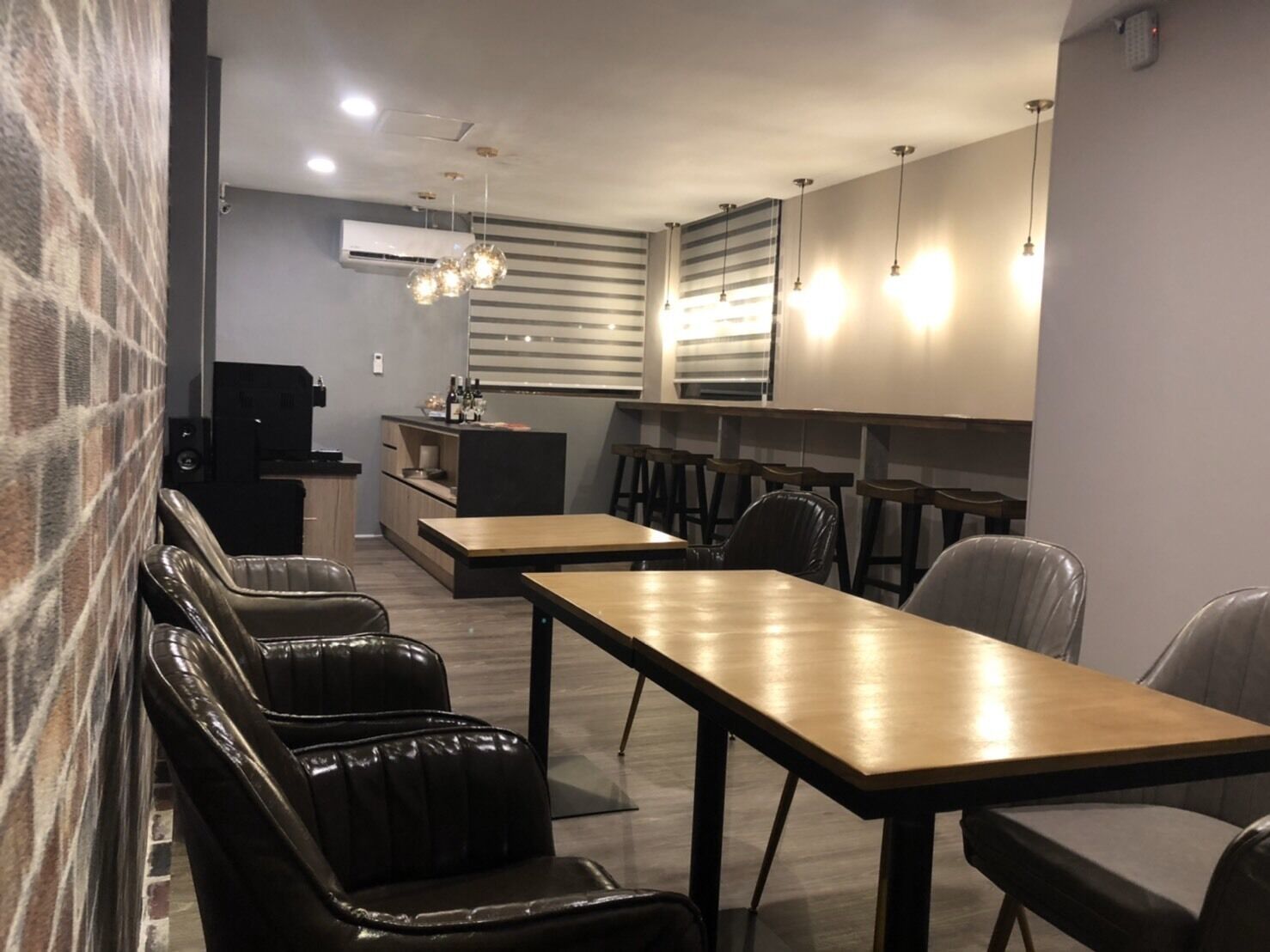A modern kitchen with a bar area, leather seating, and pendant lighting.