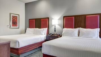 Habitación de hotel con dos camas, una mesita de noche, una lámpara y un cuadro en la pared.