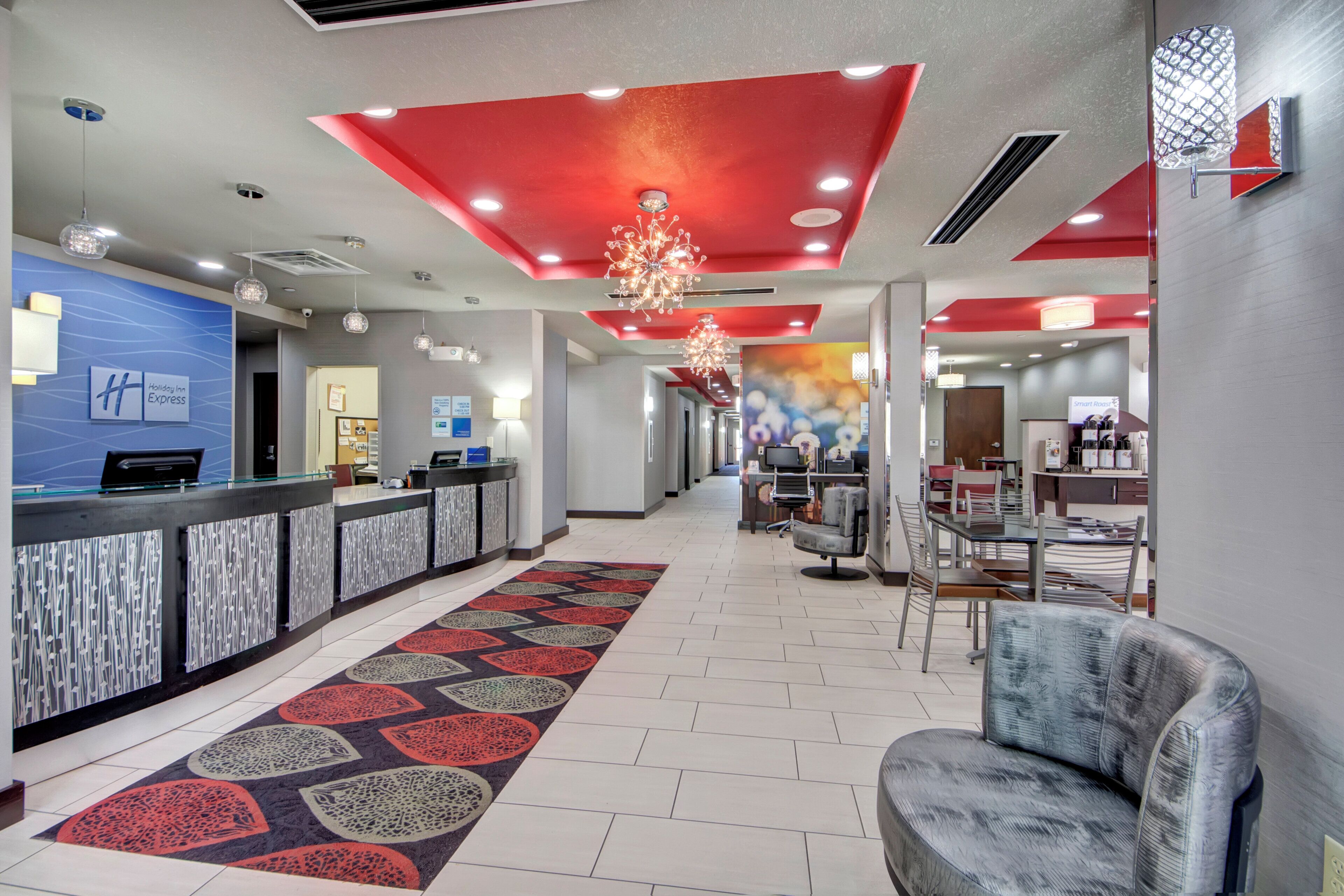 Zona de recepción de hotel con diseño moderno, que incluye un mostrador de recepción, área de descanso y un pasillo que conduce a otras habitaciones.
