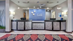 A reception area with two reception desks, a blue wall with the Holiday Inn Express logo, and a patterned carpet.