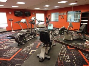 Un gimnasio con cintas de correr, elípticas y bicicletas estáticas.