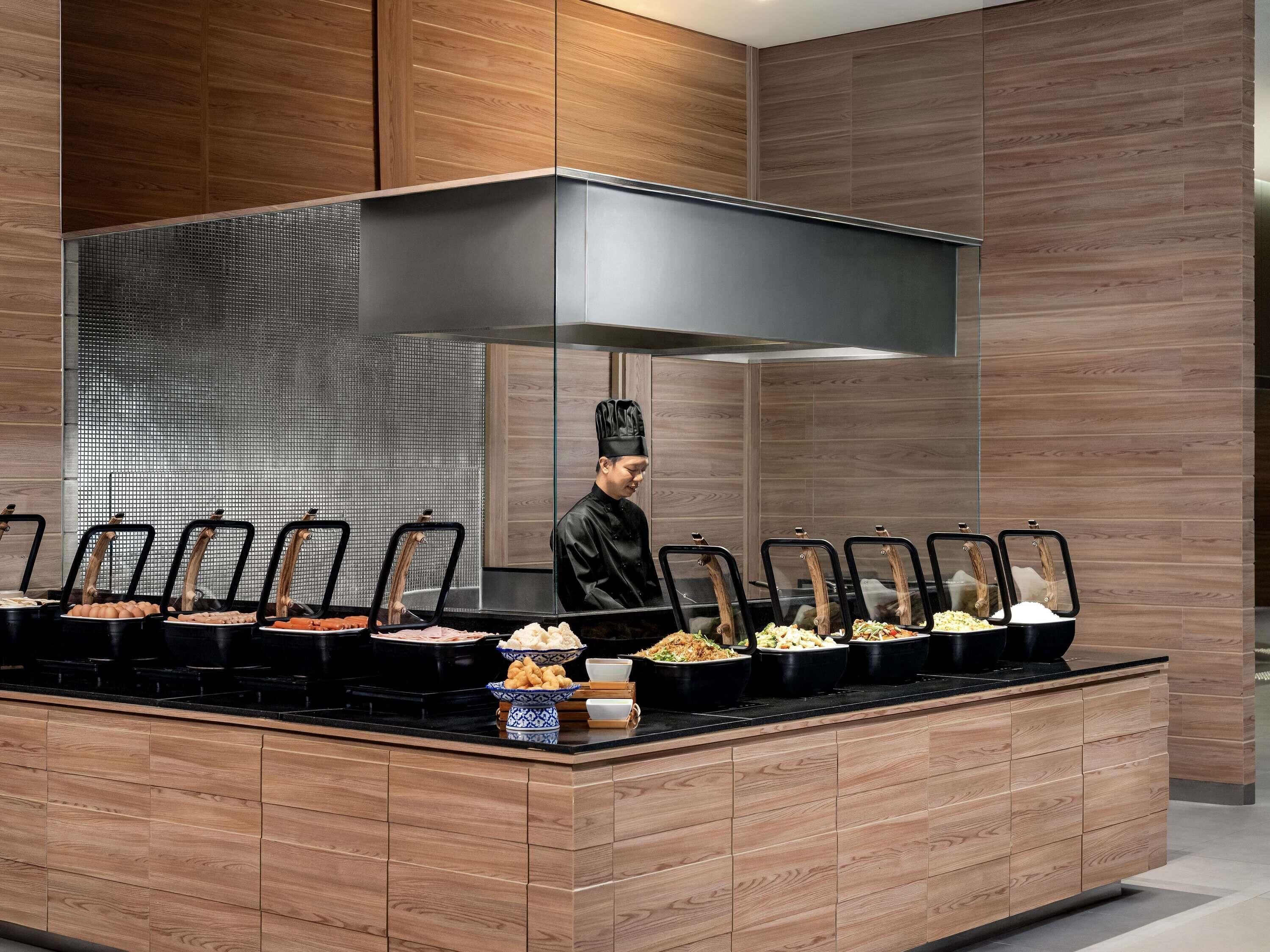 Montaje de bufé con varias estaciones de comida, un chef y un diseño de cocina moderno.