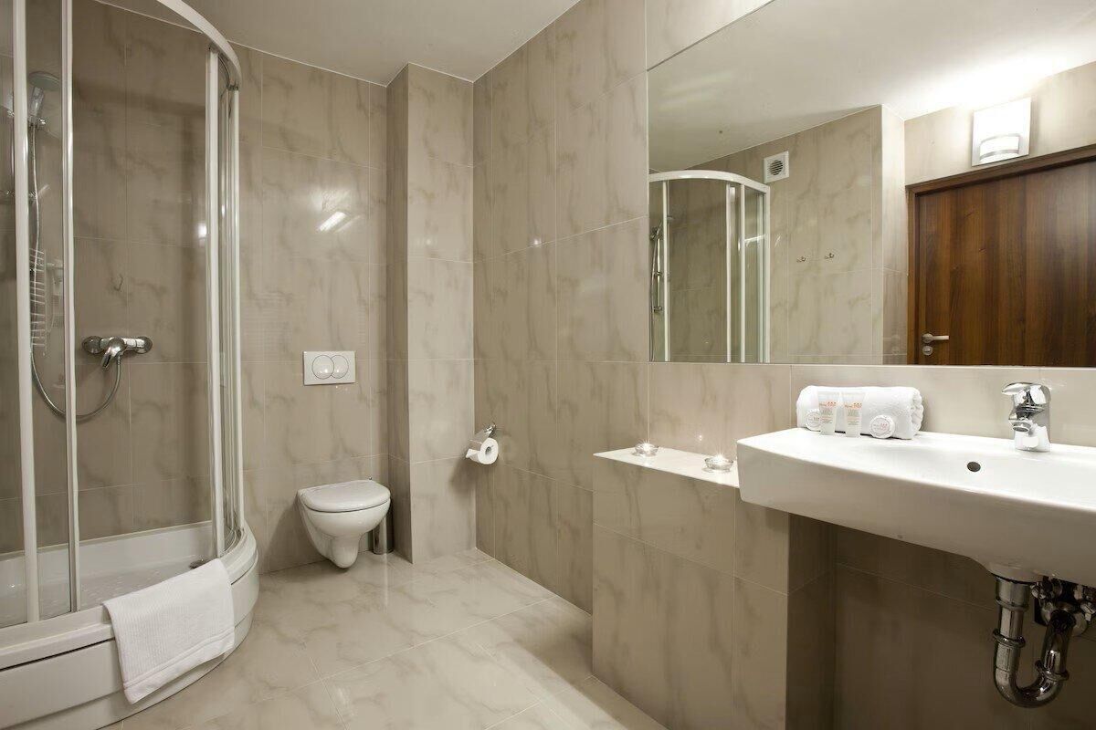 A modern bathroom with a glass-enclosed shower, a toilet, and a sink with a mirror above it.