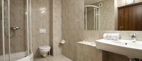 A modern bathroom with a glass-enclosed shower, a toilet, and a sink with a mirror above it.