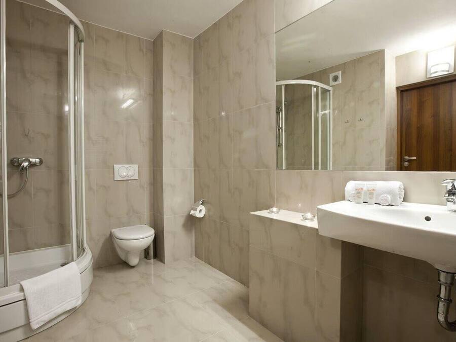 Ein modernes Badezimmer mit einer Duschkabine, einer Toilette und einem Waschbecken mit Spiegel darüber.