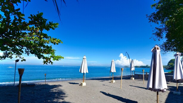 Ein Strand mit Sonnenschirmen und einem Holzzaun.