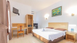 Ein Hotelzimmer mit einem Bett, einem Schreibtisch, einem Stuhl, einem Kleiderschrank und einem an der Wand montierten Fernseher.