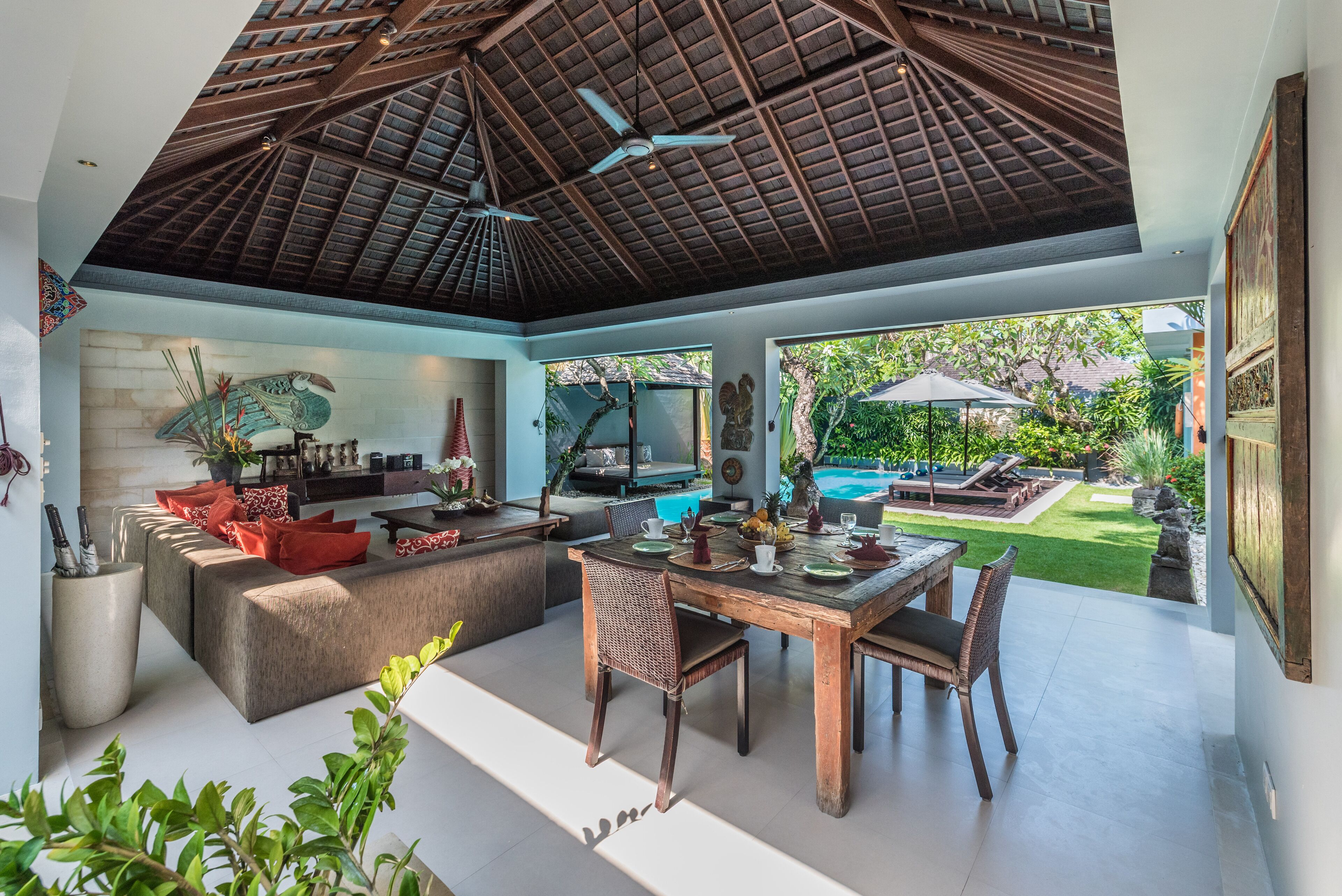 A spacious living area with a high ceiling, a dining table set for four, and a comfortable seating area.