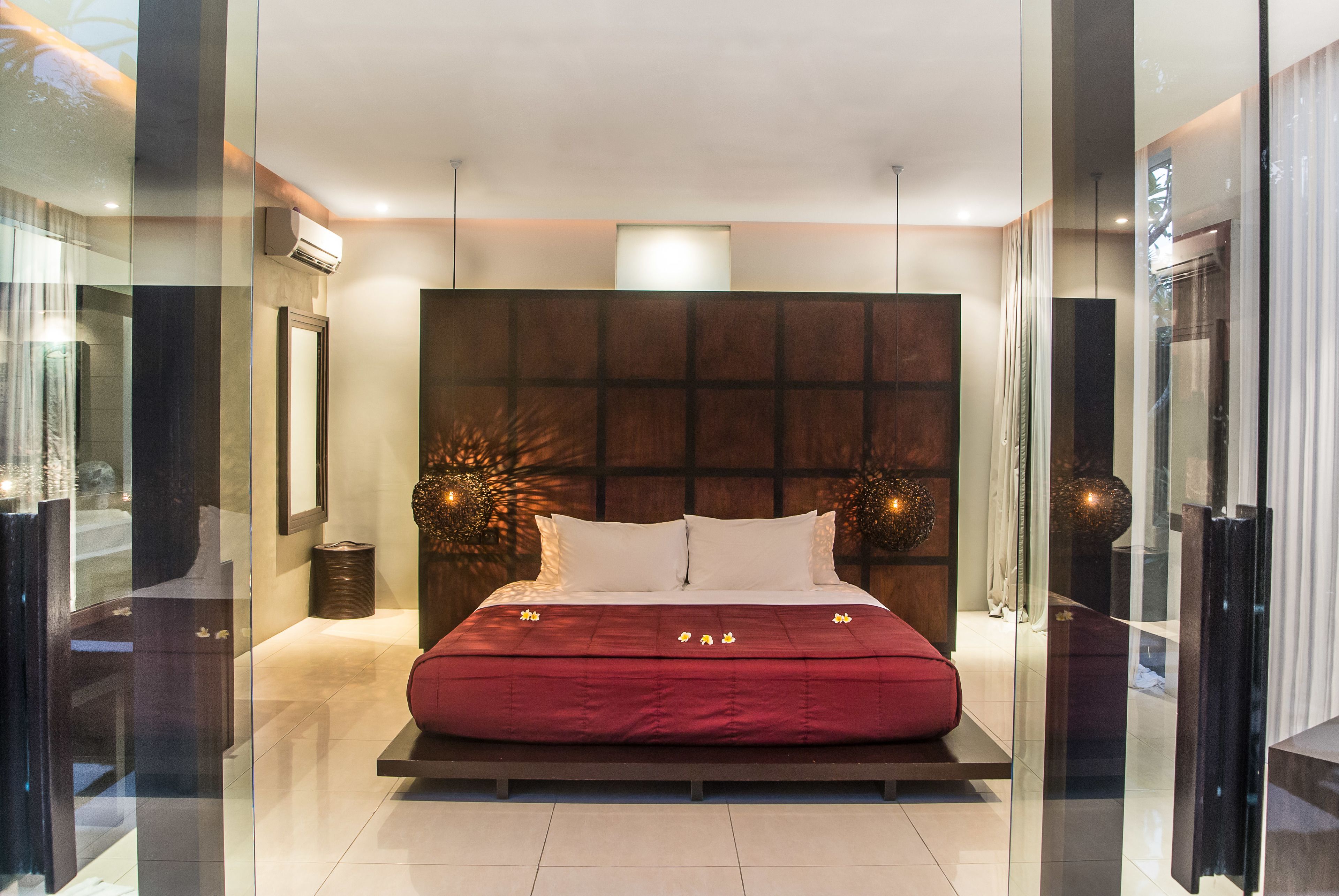 Una camera da letto moderna con un letto grande, una testiera in legno e un divisorio in vetro.