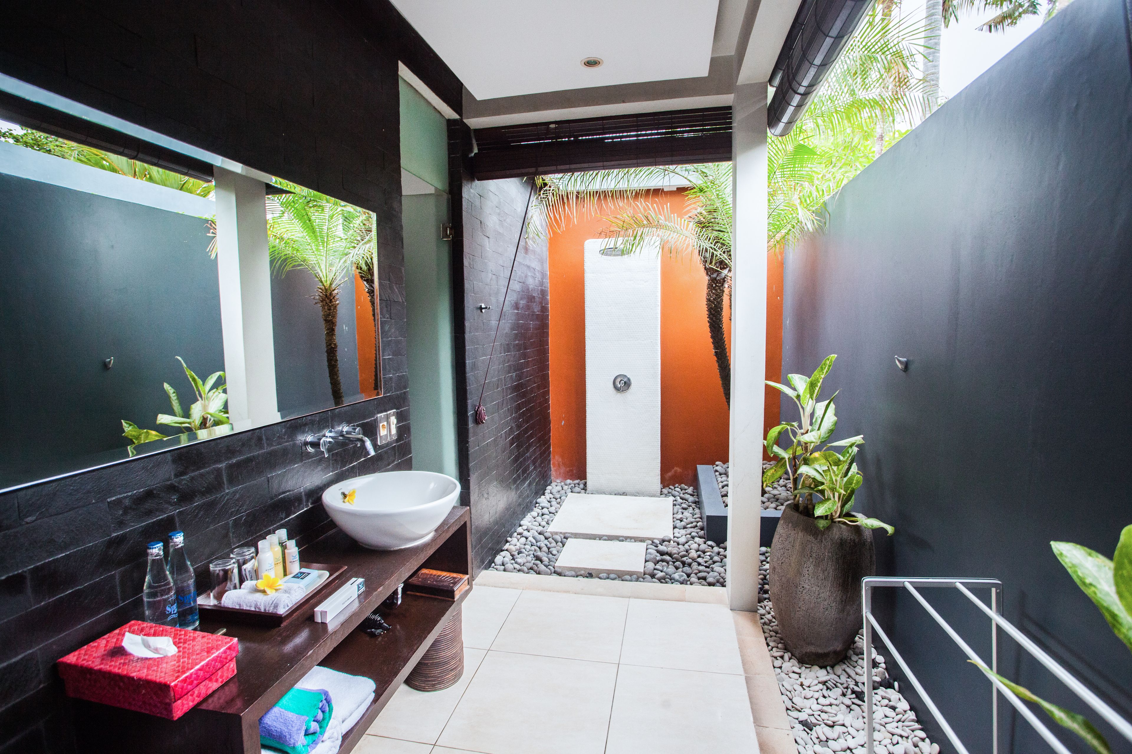 A modern bathroom with a large mirror, a white sink, and a shower area.