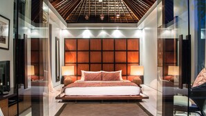 A modern bedroom with a large bed, two bedside tables, and a ceiling with a wooden design. - Kembali Villas (Seminyak)