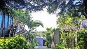 A lush garden with various tropical plants and a small structure in the center. - The Kawan Jimbaran (Ungasan)