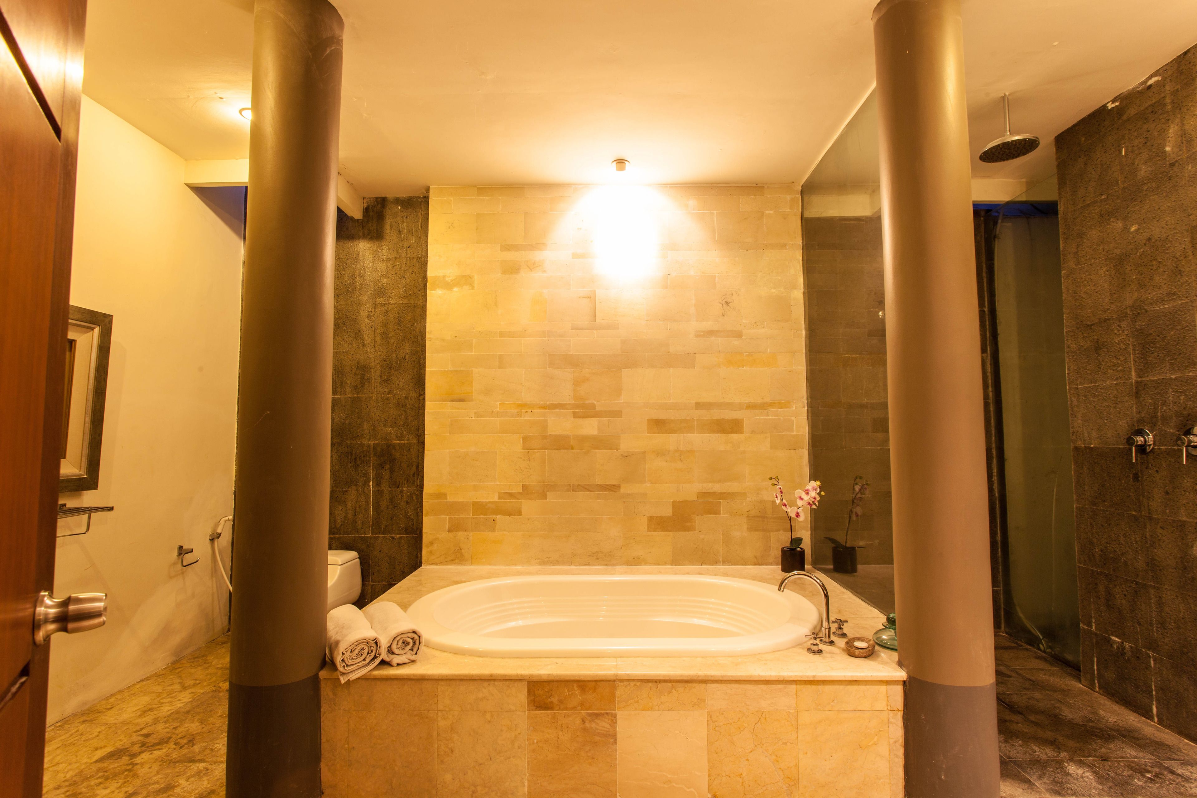 A modern bathroom with a freestanding bathtub, stone tiles, and a large mirror.