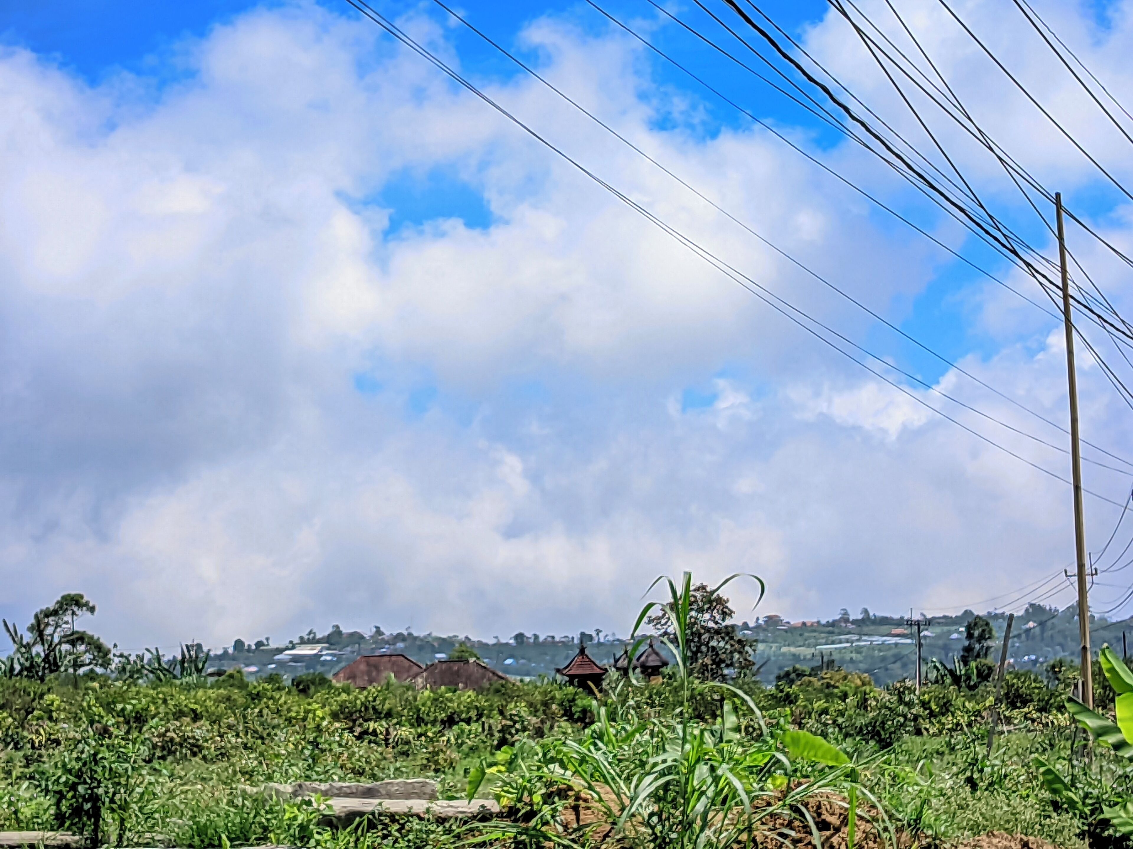 A rural landscape with fields, a few buildings, and a clear sky.