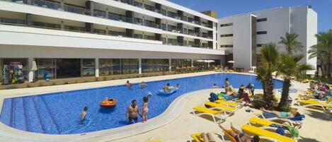 A pool area with multiple levels of balconies, sun loungers, and a clear blue sky.