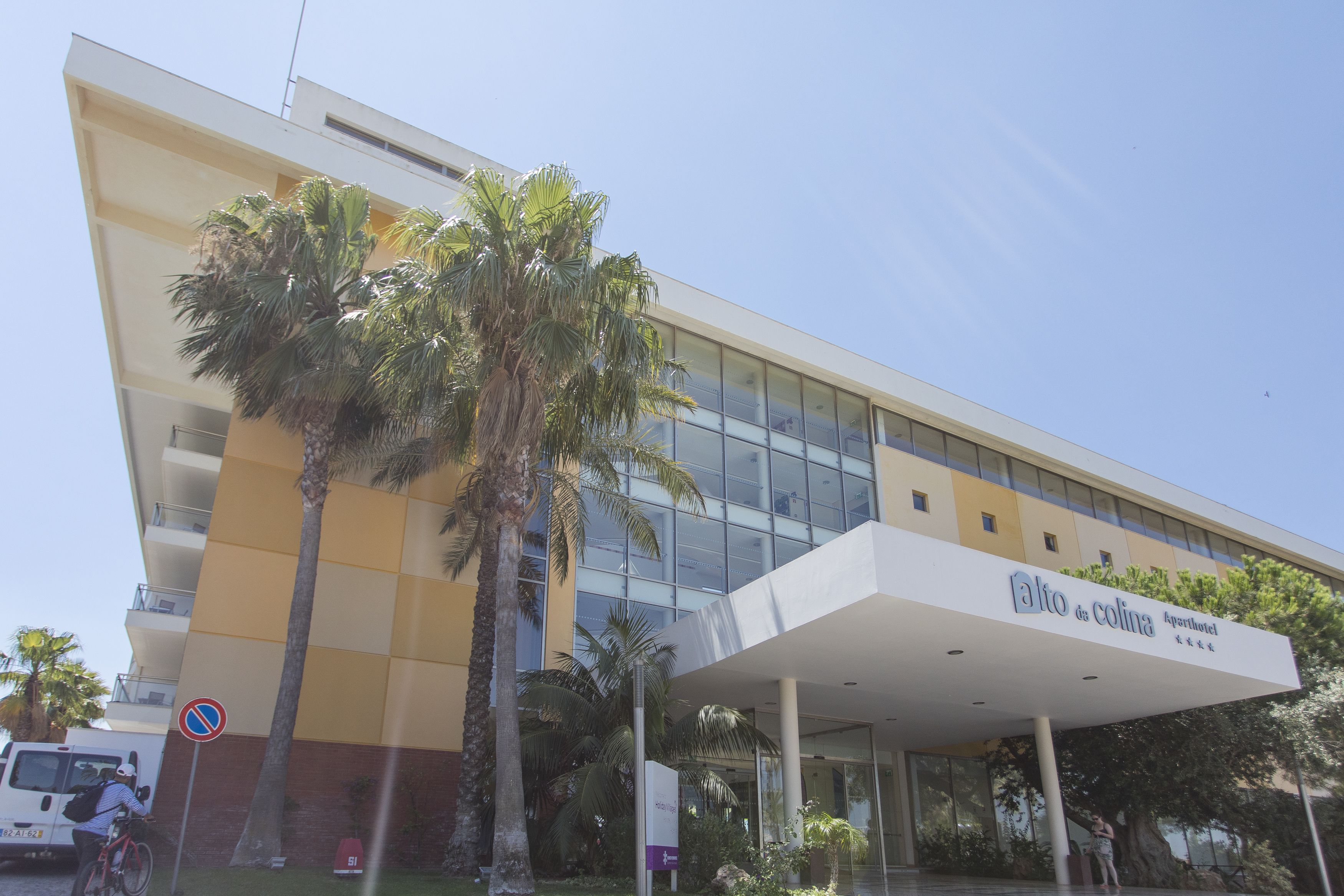 A modern building with a sign reading "alto da colina Apartotel".