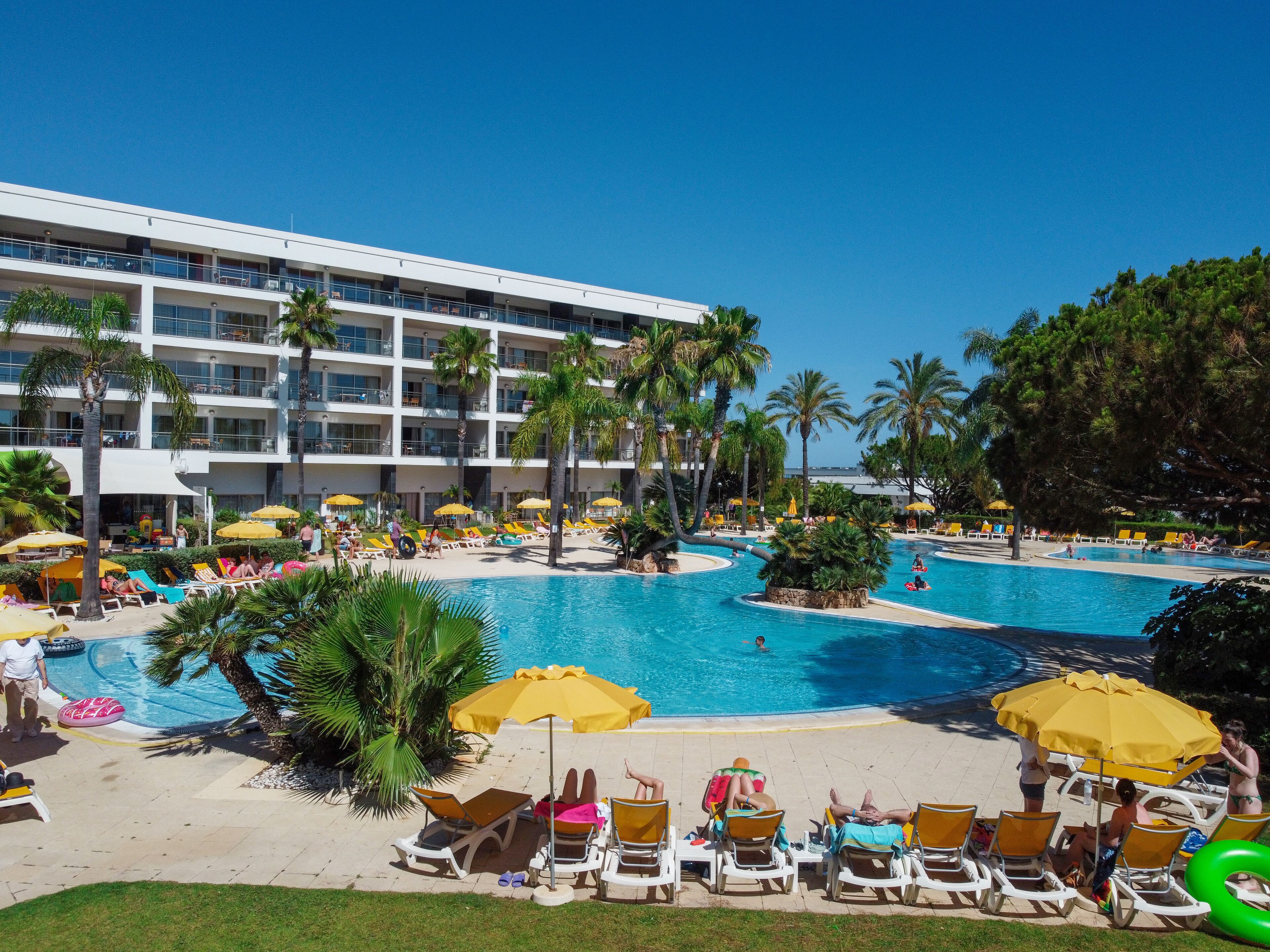 A resort with multiple swimming pools, sun loungers, and palm trees.