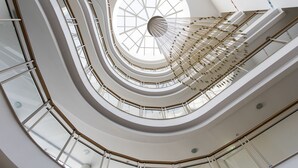 Ein mehrgeschossiges Atrium mit einer zentralen Wendeltreppe und Glasgeländern.