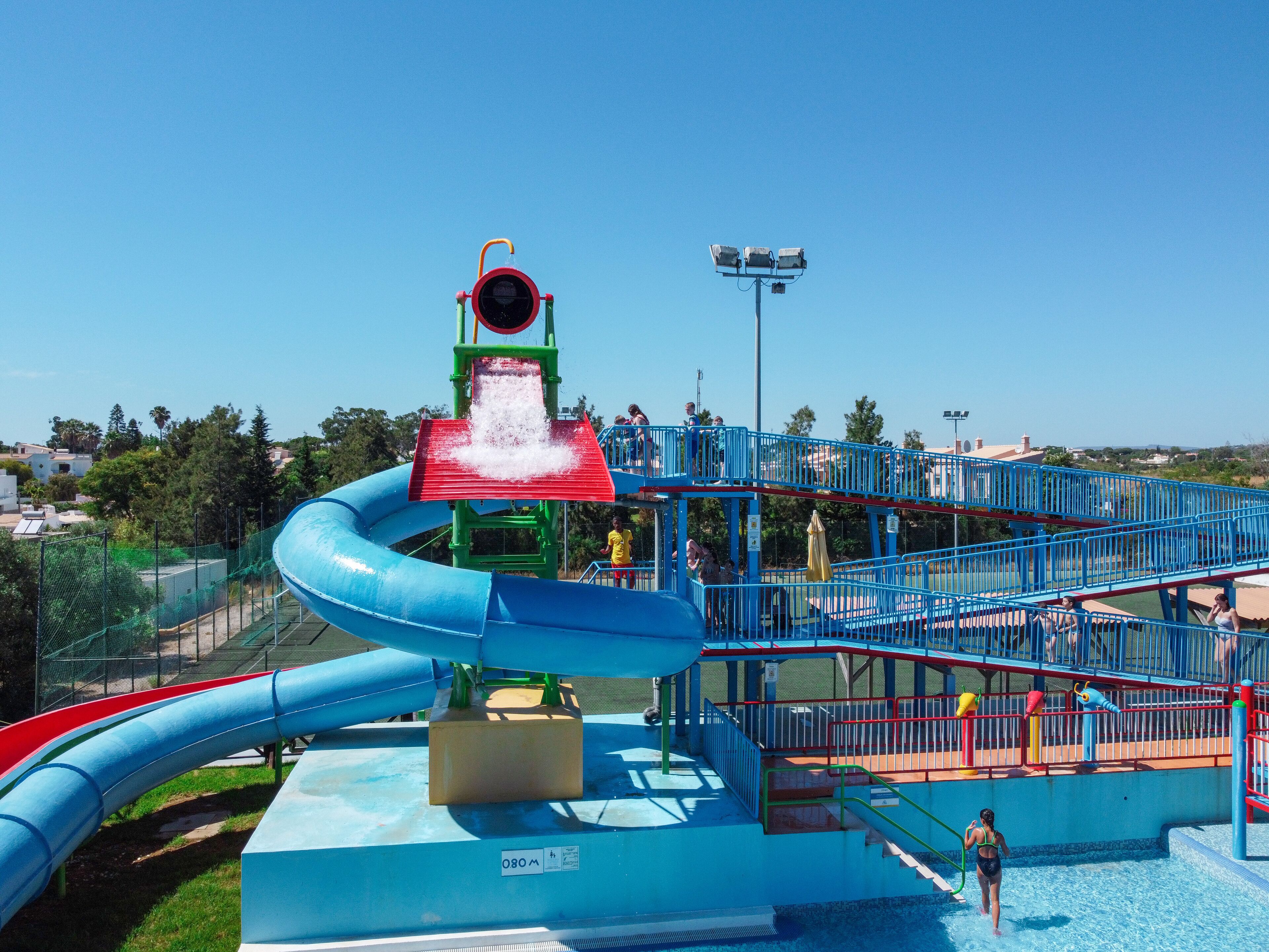 A water park with a large blue water slide, a red water slide, and a water play area.