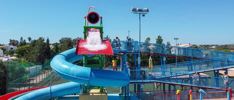 A water park with a large blue water slide, a red water slide, and a water play area.