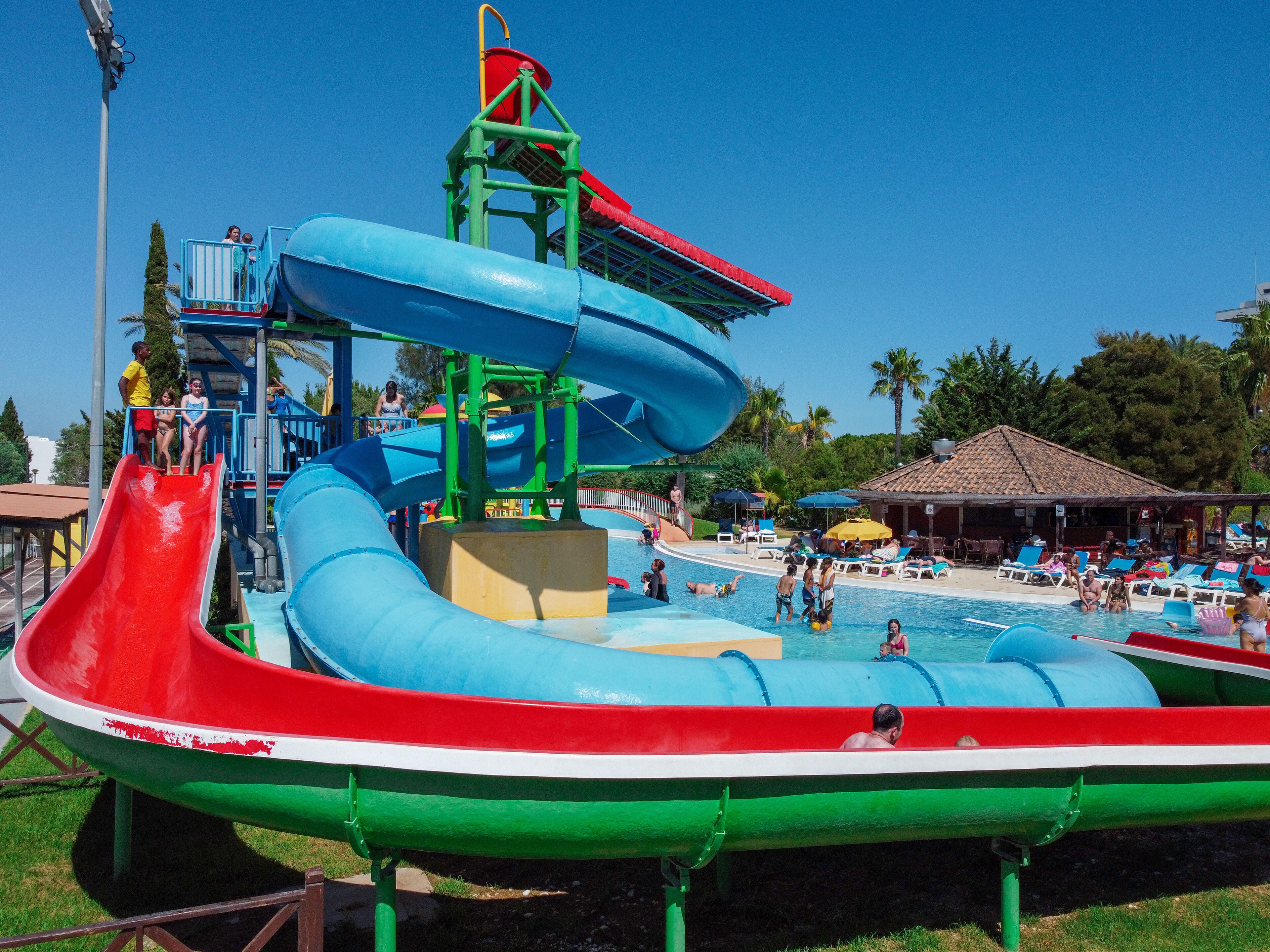 A water park with a large water slide, a pool area with lounge chairs, and a covered seating area.
