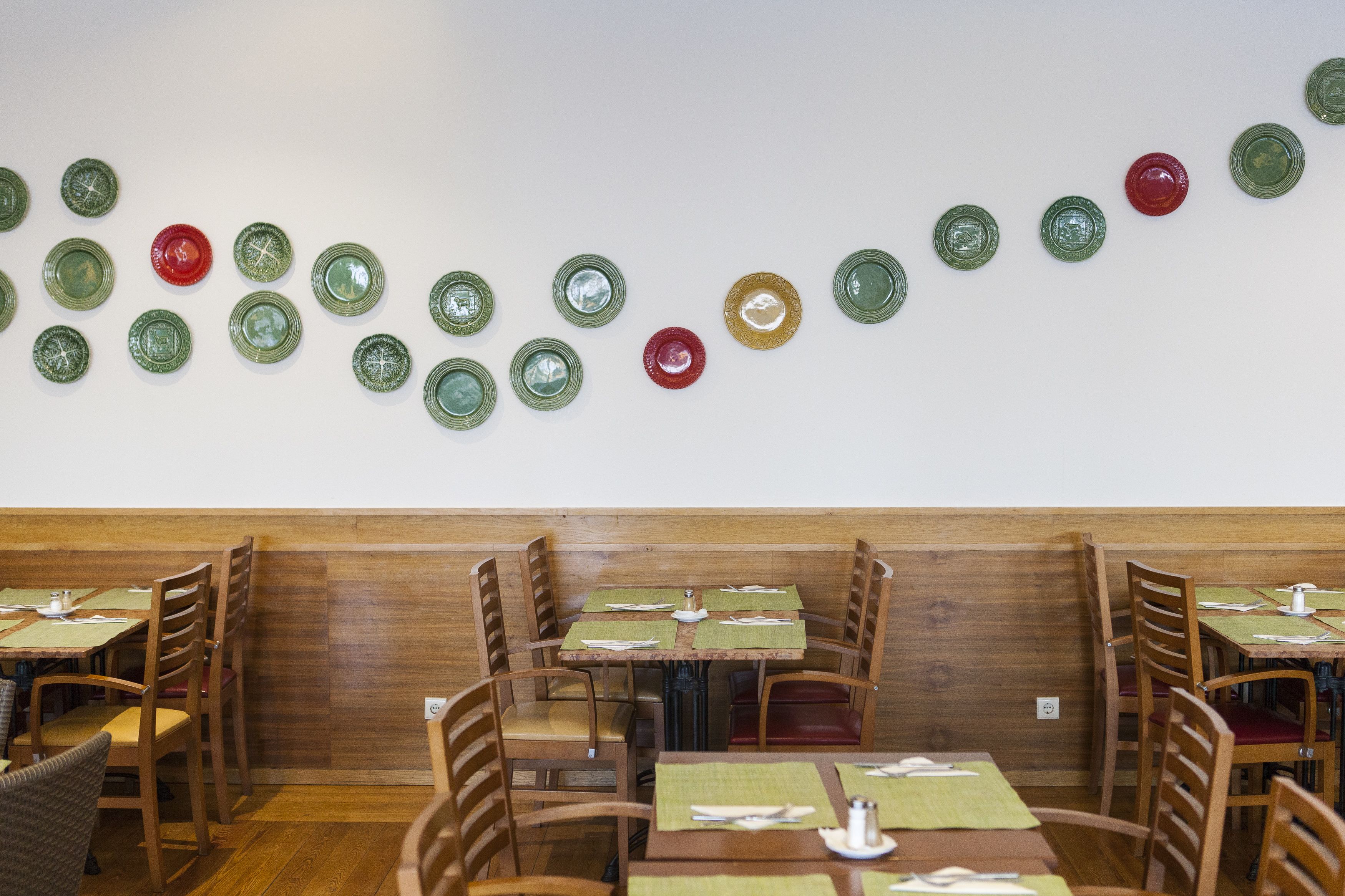 Interior de restaurante con cabinas y mesas de madera, algunas con manteles individuales verdes.