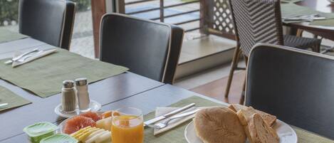 Una mesa de desayuno dispuesta con platos de comida, una taza de café y vistas al exterior.