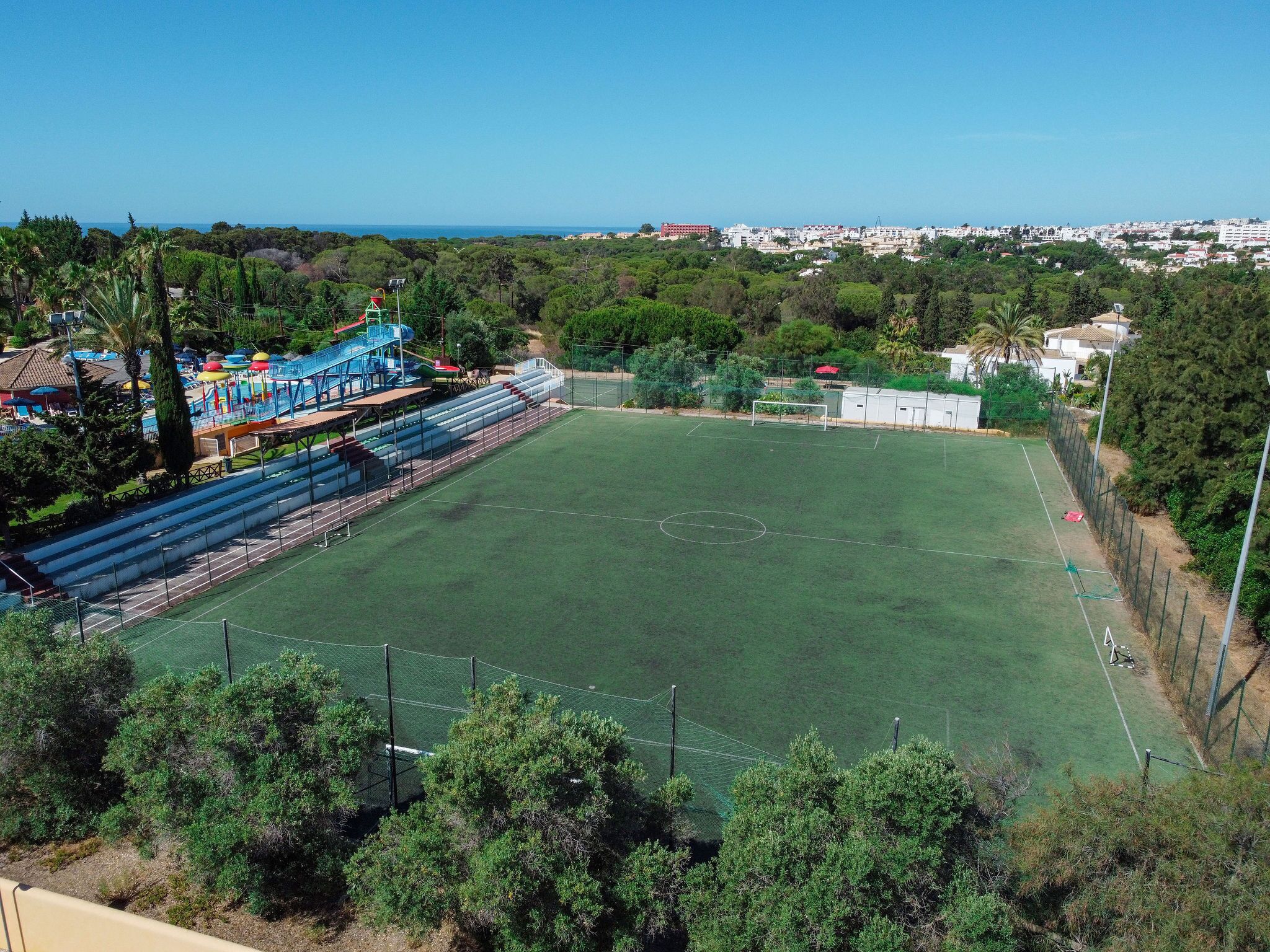 Un campo deportivo amplio y abierto con gradas y un pequeño edificio al fondo.