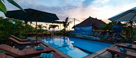 Una piscina al aire libre, sombrillas, sillones reclinables de piscina