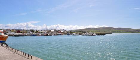 A coastal town with a marina, boats docked, and a clear sky.