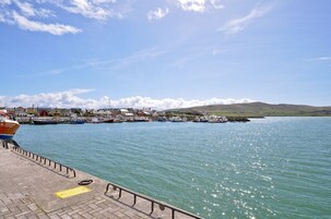 Un pueblo costero con un puerto deportivo, barcos amarrados y un cielo despejado.