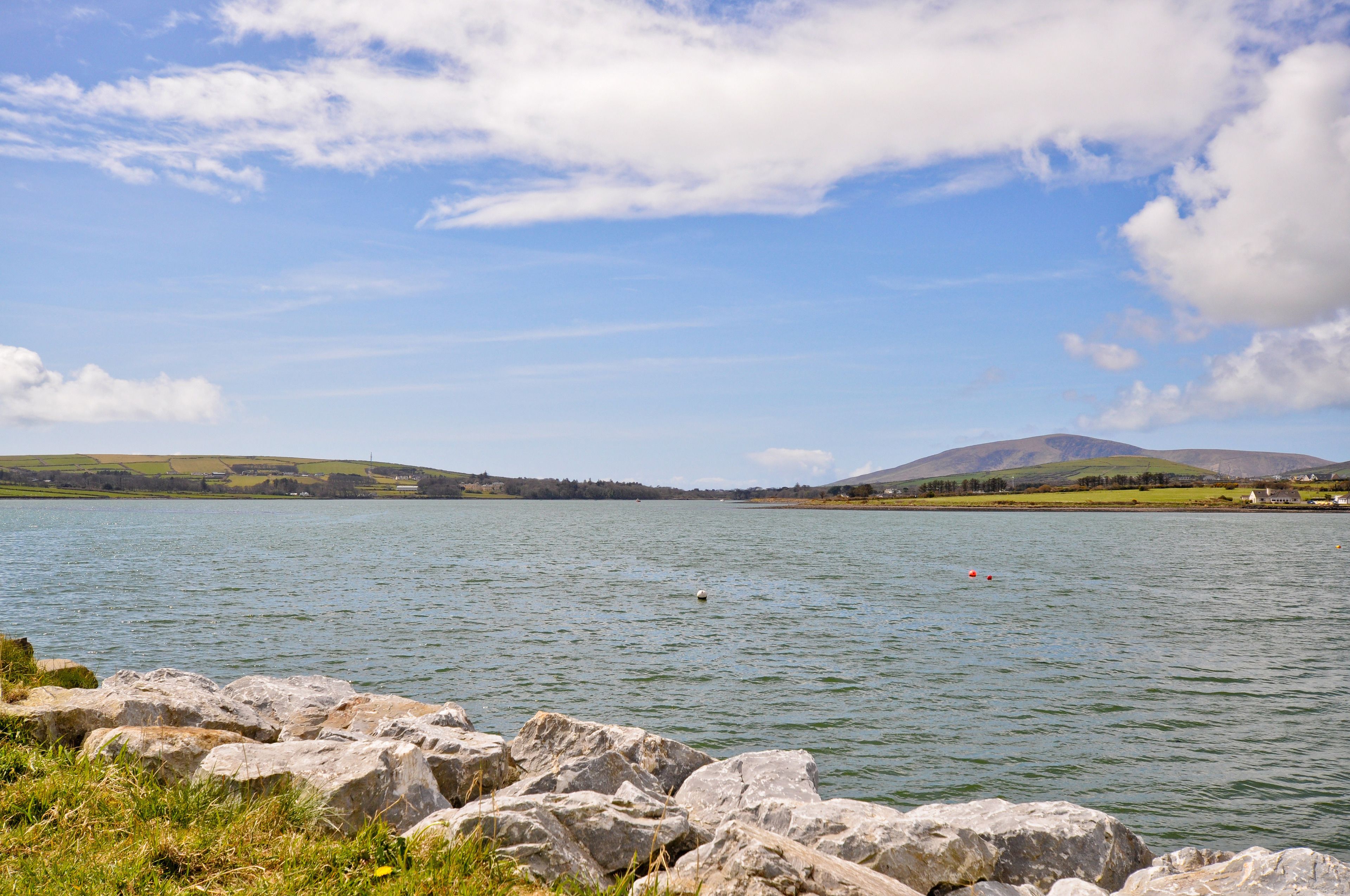 A lake with a rocky shoreline and distant hills.