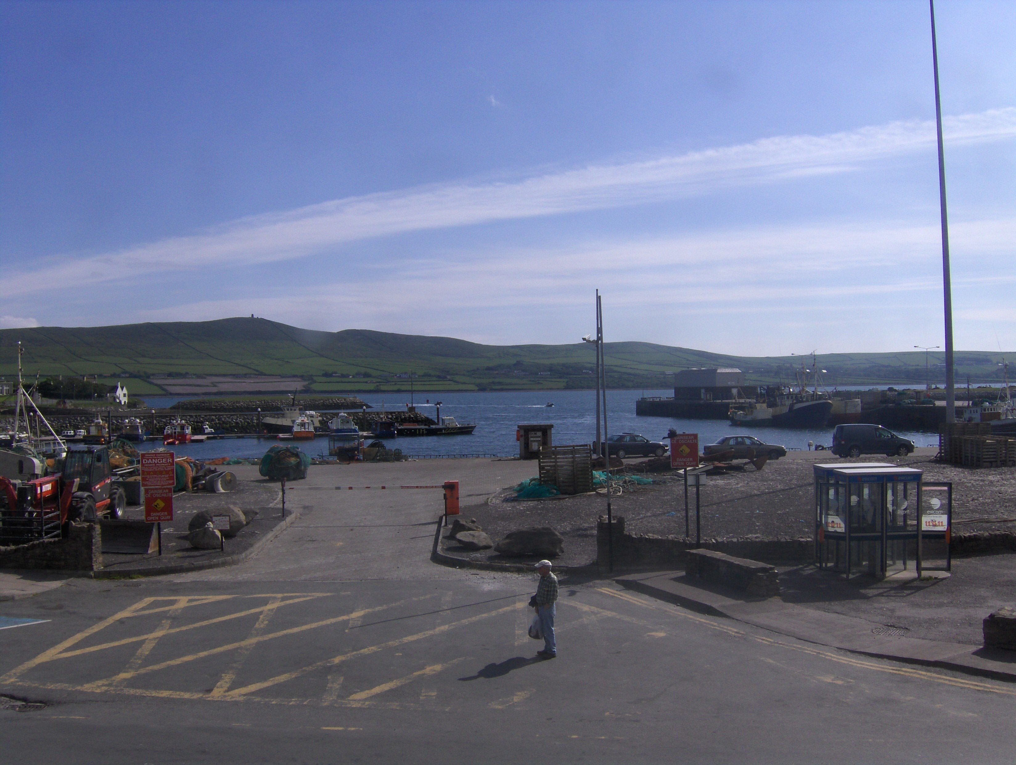 A harbor with boats, a person walking, and a clear sky.
