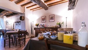 A dining area with a wooden table set for four, a buffet with various food items, and a rustic ceiling with exposed beams. - Il Vignolino Bed and Breakfast (Barberino di Mugello)