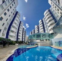 Un hotel moderno con piscina, varios balcones y fachada de vidrio.