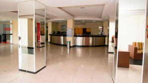 A hotel lobby with a reception desk, seating area, and a trash bin.