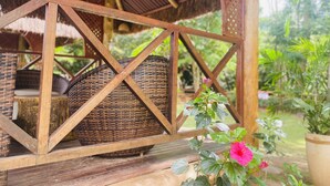 Ein hölzerner Pavillon mit gewobenen Stühlen und einem Blumentopf mit rosa Blüten.