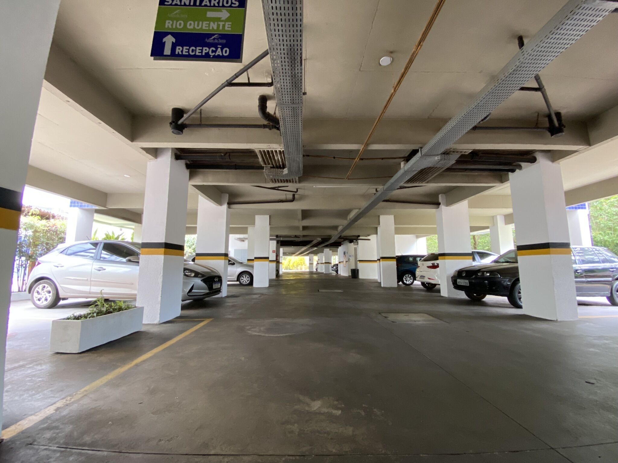 A parking garage with multiple levels, concrete pillars, and directional signs.
