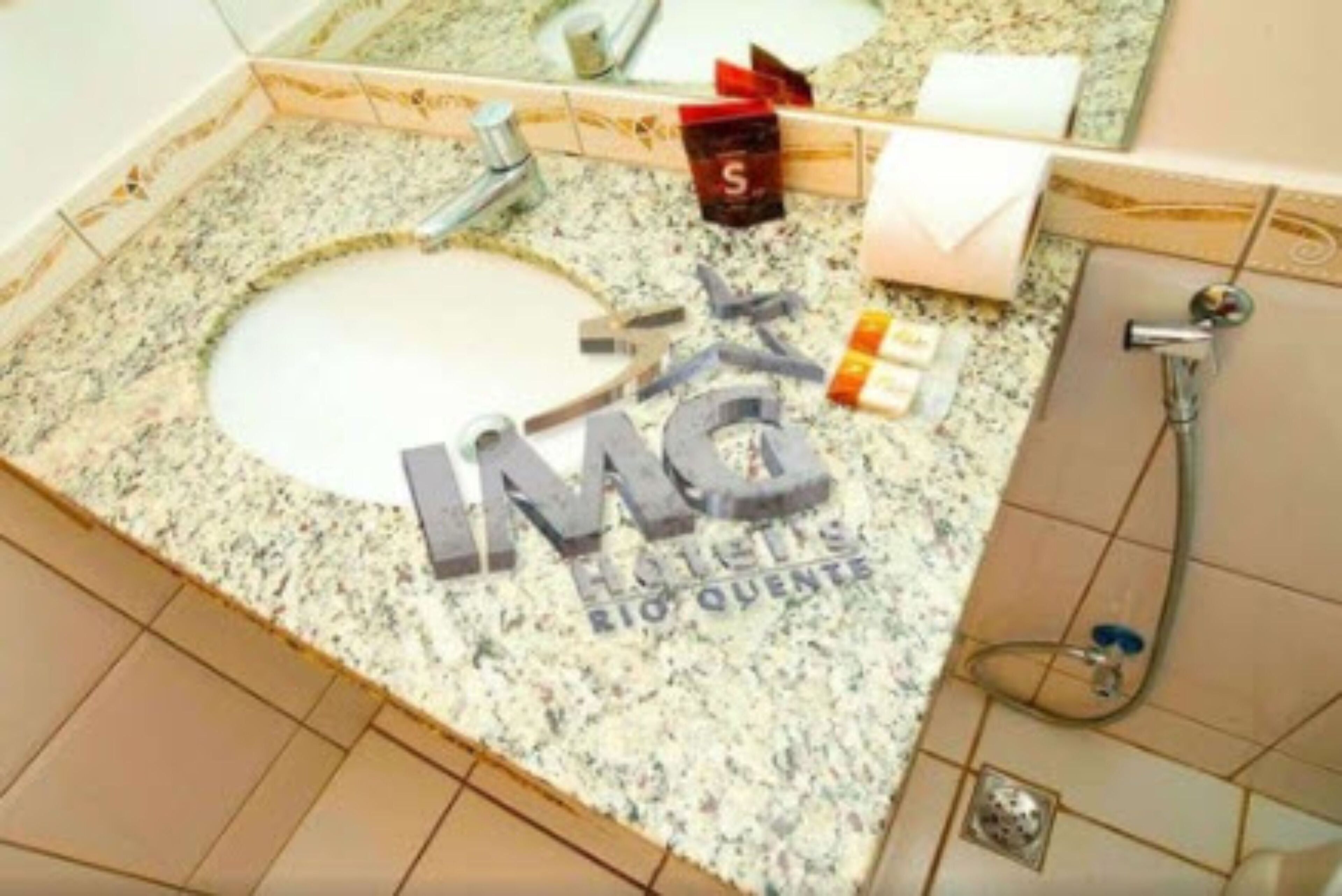 Een badkamer met een granieten aanrechtblad, een wastafel, een spiegel, een zeepdispenser en een douche.