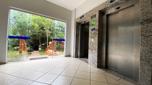 Ein moderner Aufzugsbereich mit Glastür und Blick auf einen Garten.