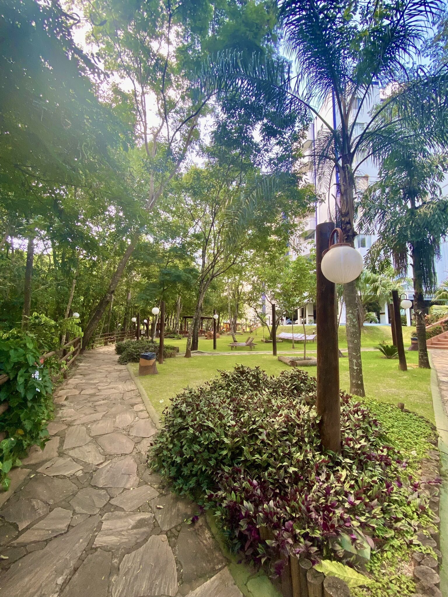 Un chemin de pierre qui traverse un parc, avec des bancs et des lampadaires.